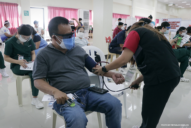 A BMC personnel checks the vital signs of Dr. Azuero Baesa of City Health Office 30 minutes after he received a dose of AstraZeneca vaccine.