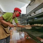 A Siopao Factory baker placing a new batch of dough into the oven