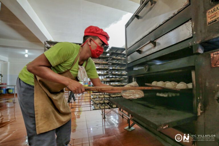 A Siopao Factory baker placing a new batch of dough into the oven