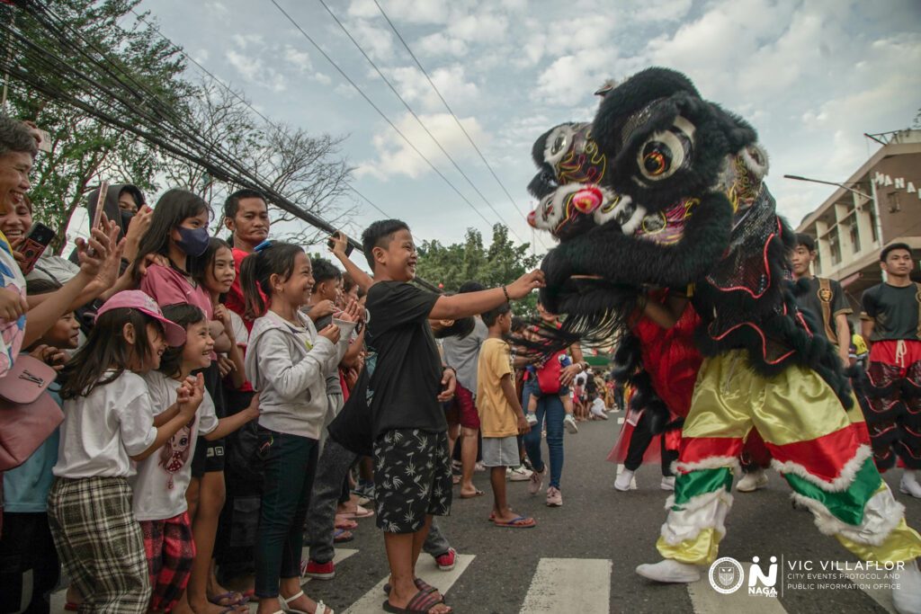 A child petting one of the puppeteered Lions from Saint Joseph School's Lion Danceers.