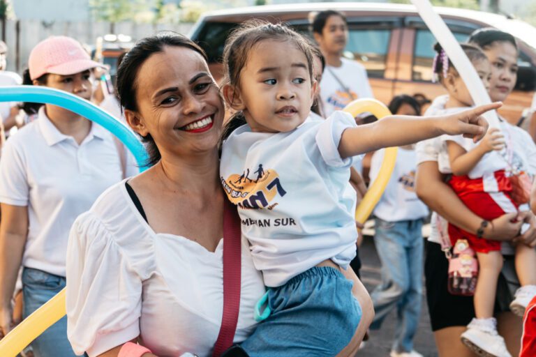 A photo of a Nagueña mother carrying her child during one of the city's children-centered events titled, "Lakaw Para Sa Kaakian 2023"